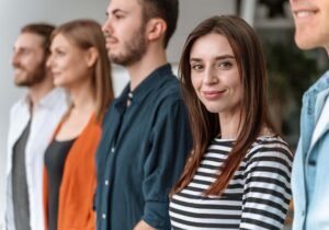 Woman smiling in your direction standing besides other young folks